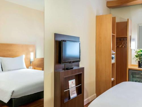 um quarto de hotel com uma cama e uma televisão de ecrã plano em Ibis Izmir Alsancak em Esmirna