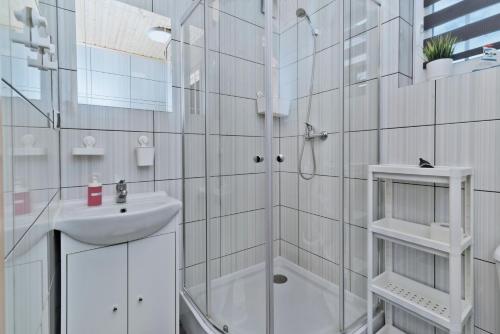 a white bathroom with a sink and a shower at Domki letniskowe Kajuta in Władysławowo