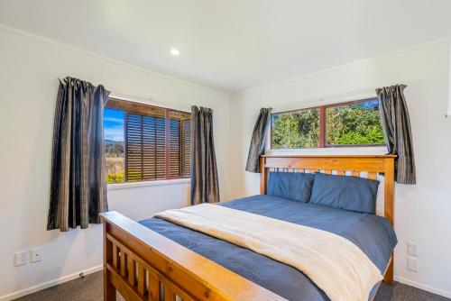 a bedroom with a bed and two windows at Cottage on Rutherford - Waikanae Holiday Home in Waikanae