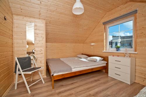 a bed in a room with a window and a chair at Domki letniskowe Kajuta in Władysławowo