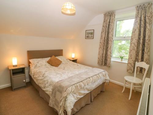 a bedroom with a bed and a window and a chair at Garreg Lwyd Farm in Pwllheli