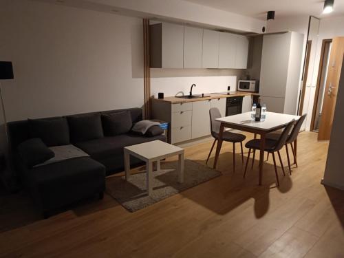 a living room with a couch and a table and a kitchen at Apartament z Ogrodem Gdansk Przymorze in Gdańsk
