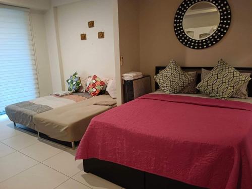 1 dormitorio con 2 camas y espejo en la pared en Pico Beach Front Condo, en Nasugbu