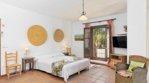 een slaapkamer met een bed en stoelen en een televisie bij Casa La Loma del Sabinal Alora by Ruralidays in Alora