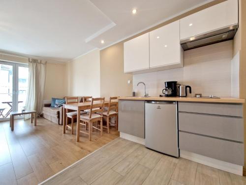 a kitchen and living room with a table and chairs at Apartbaltic - Mistral 21 in Świnoujście