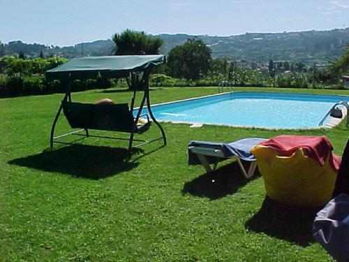 a man sitting in a chair next to a swimming pool at Stone Farm Hostel in Felgueiras