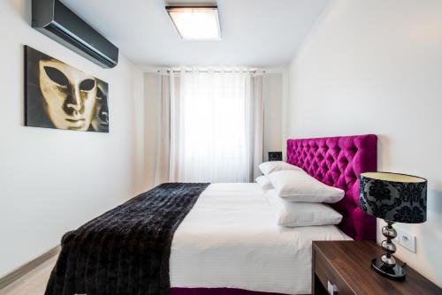a bedroom with a large bed with a purple headboard at Centrum Superior Suites in Białystok