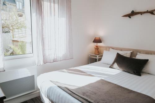 a bedroom with a bed with white sheets and a window at Hôtel Aux Tamaris - Vue Mer in Roscoff