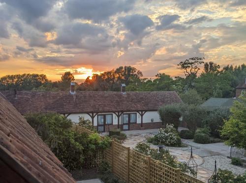 una vista de una casa con la puesta de sol en el fondo en Kingfisher Barn B&B, en Abingdon