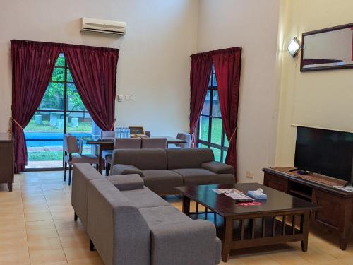 een woonkamer met banken en een flatscreen-tv bij Serene Holiday Chalet with pool in a quiet enclave in Kampong Alor Gajah