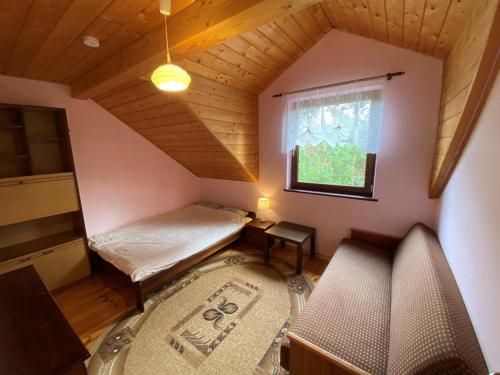 a small attic room with a bed and a window at Dom w Puszczy Augustowskiej in Płaska
