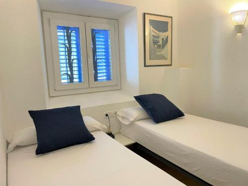 two beds in a room with two windows at PALAU - Gran casa de pueblo con fantásticas vistas al mar in Cadaqués
