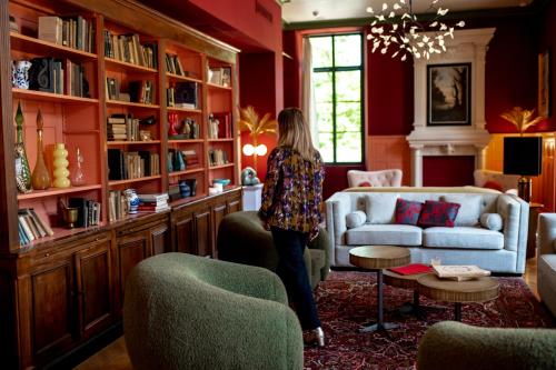 a woman standing in a living room with a couch at Château de Fiac - Luxurious Hôtel & Spa in Fiac