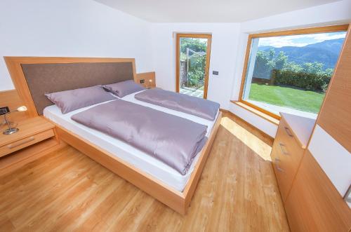 ein Schlafzimmer mit einem großen Bett und einem großen Fenster in der Unterkunft Avea App 1 in Lajen