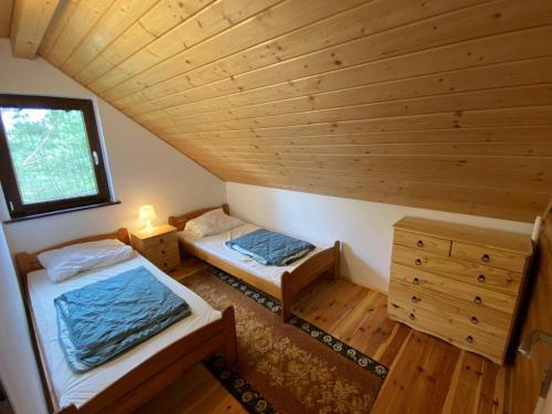 two beds in a room with a wooden ceiling at Domek apartament w Puszczy Augustowskiej in Płaska