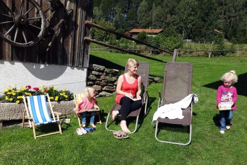 een vrouw en drie kinderen zittend in tuinstoelen bij Urlaub auf dem Haberlhof in Lohberg