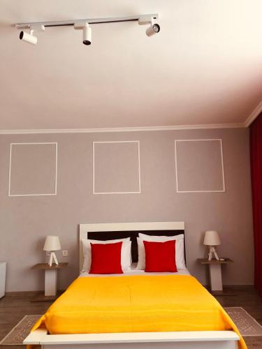 a bedroom with a yellow bed with two red pillows at Hotel Tamar Mepe in Kutaisi