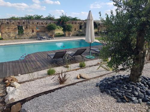 une piscine avec un parasol, des chaises et un arbre dans l'établissement Le clos du Mûrier, à Fongrave