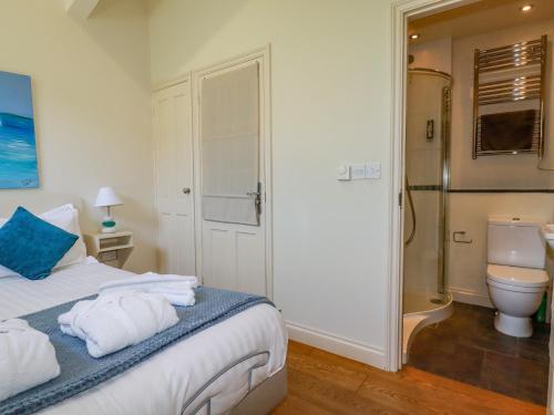 a bedroom with a bed and a bathroom with a shower at Periwinkle in Bude
