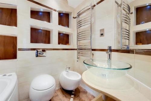a bathroom with a glass sink and a toilet at Stanhope Terrace in London