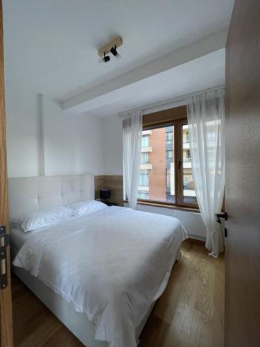 a bedroom with a large white bed and a window at Apartman Zlatibor Centar in Zlatibor