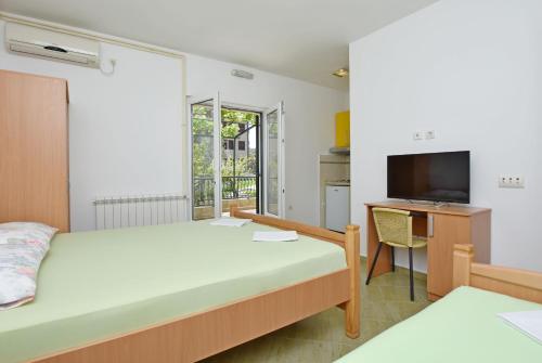 a bedroom with a bed and a desk and a television at Apartments and Rooms Iva in Petrovac na Moru