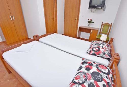 two beds in a small room with a tv at Apartments and Rooms Iva in Petrovac na Moru