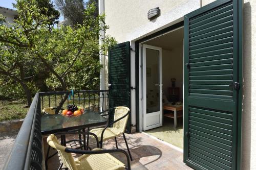 a table and chairs on a patio with a green door at Apartments and Rooms Iva in Petrovac na Moru