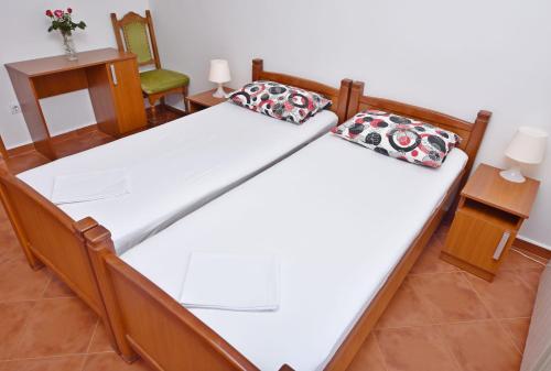 two beds in a room with two chairs at Apartments and Rooms Iva in Petrovac na Moru