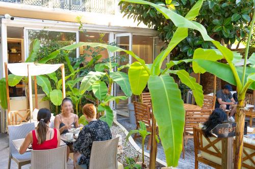 a group of people sitting at a table in a garden at Auberge de Jeunesse HI Nice Les Camélias in Nice