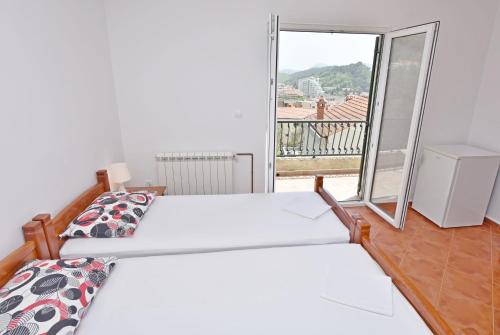 a bedroom with two beds and a balcony at Apartments and Rooms Iva in Petrovac na Moru