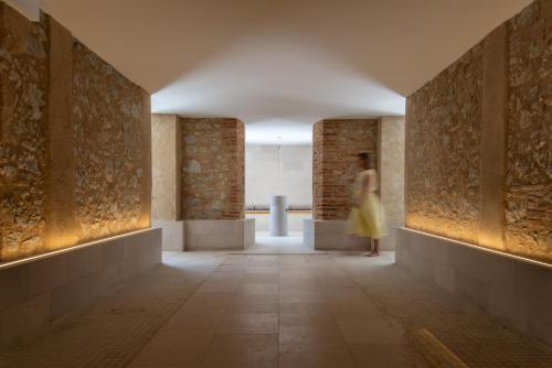 a woman in a yellow dress walking down a hallway at Château de Fiac - Luxurious Hôtel & Spa in Fiac