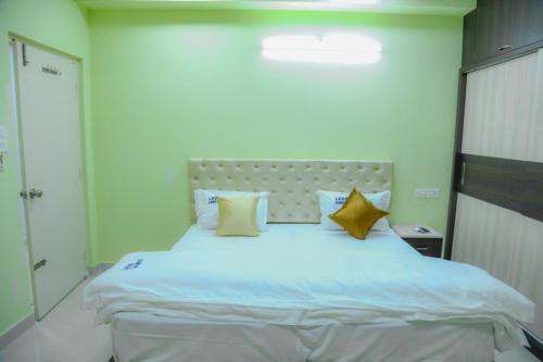 1 dormitorio con 1 cama blanca grande con almohadas amarillas en Leeo Comforts en Visakhapatnam
