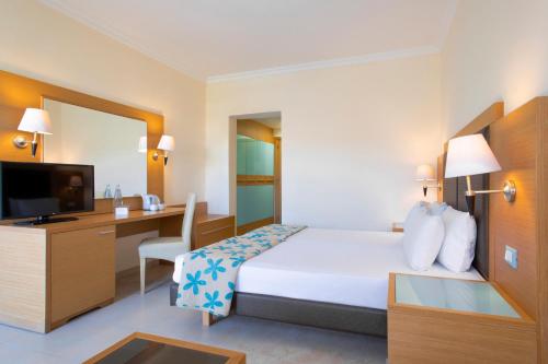 a hotel room with a bed and a desk and a television at Sol Cosmopolitan Rhodes in Ixia