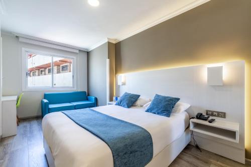 a hotel room with a bed and a blue chair at Hotel Atlántico Vigo in Vigo
