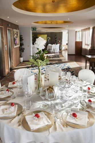 a table with glasses and a vase of flowers on it at City Hotel in Senigallia