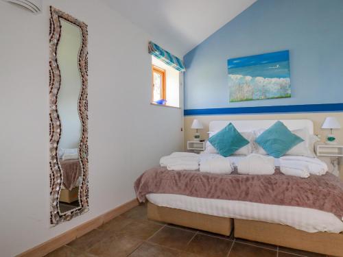 a bedroom with a bed with blue walls and a mirror at Seashells in Bude