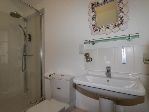 a bathroom with a toilet and a sink and a shower at Seashells in Bude
