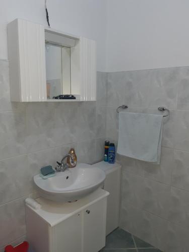 een witte badkamer met een wastafel en een spiegel bij Apartman Čerkez in Stolac