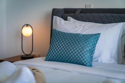 a bed with a blue pillow and a lamp at The Palmiers in Paphos City