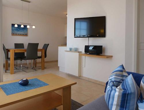 a living room with a couch and a tv on a wall at Haus Meeresblick - Ferienwohnung Schwalbennest A 4.06 (Ref. 128721) in Baabe