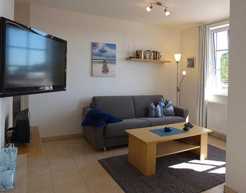 a living room with a couch and a flat screen tv at Haus Meeresblick - Ferienwohnung Schwalbennest A 4.06 (Ref. 128721) in Baabe