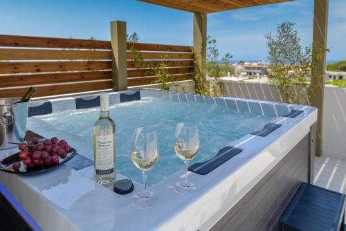 a hot tub with two glasses of wine and grapes at Atlas Villa in Kremasti