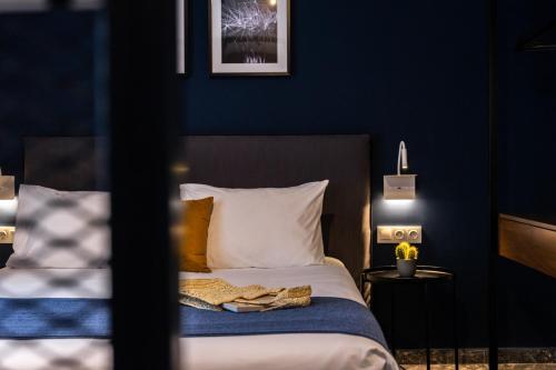 a bedroom with a bed with a blue wall at Play Theatrou Athens in Athens