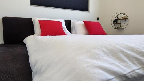 a bedroom with a white bed with red pillows at צימר גראפה בערבה - Grappa in Yahel