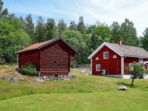 eine rote Scheune und ein rotes Haus auf einem Feld in der Unterkunft 16 person holiday home in P LSBODA in Hjortkvarn