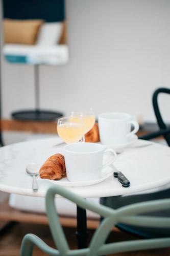 a tray with cups and croissants on a table at Les Précieuses Suites & Spa II in Avignon