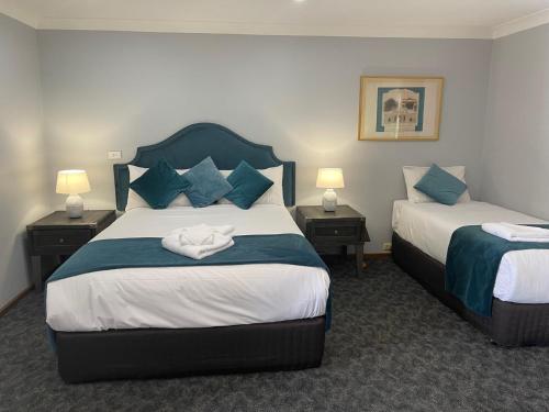 a hotel room with two beds and two lamps at Town & Country Motor Inn in Forbes