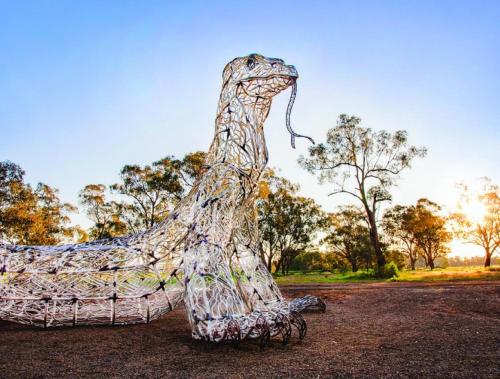 a sculpture of a dinosaur in a field at Town & Country Motor Inn in Forbes