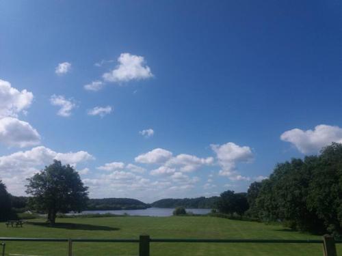a green field with a lake in the background at The Jewel in the Crown, countryside escape in Rushton Spencer